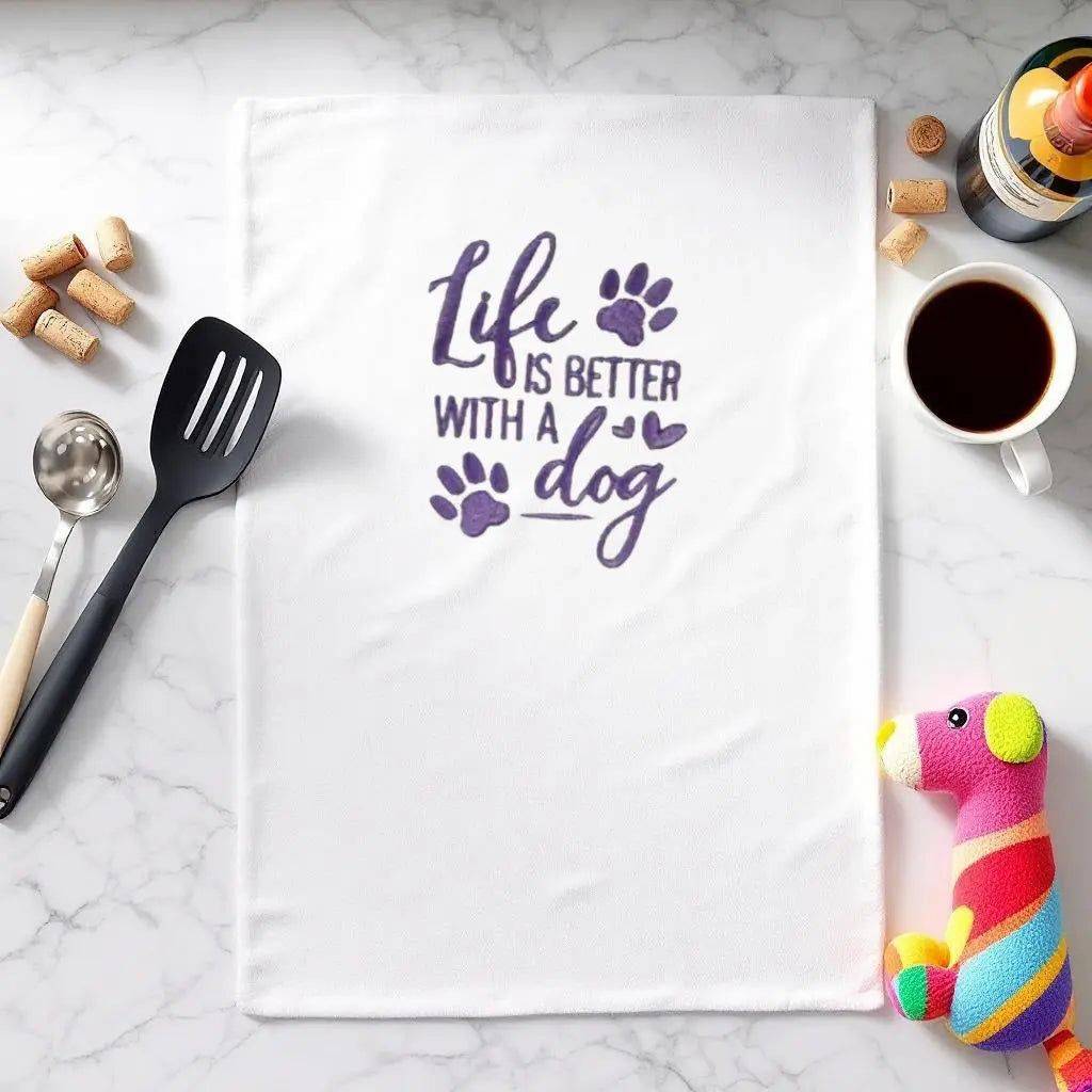 Life is Better with a Dog Towel featuring purple embroidered text and paw prints, displayed on a kitchen counter with utensils and coffee.