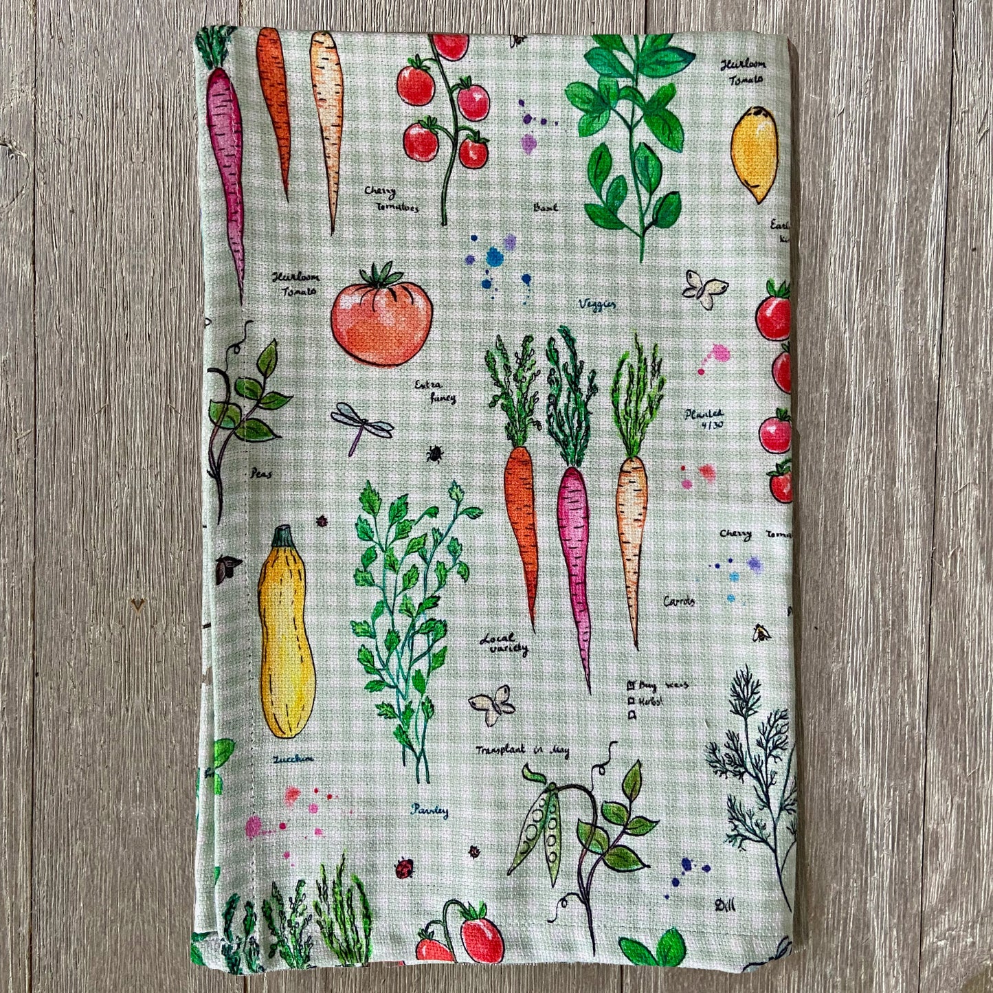 Folded vegetable pattern tea towel on wooden surface