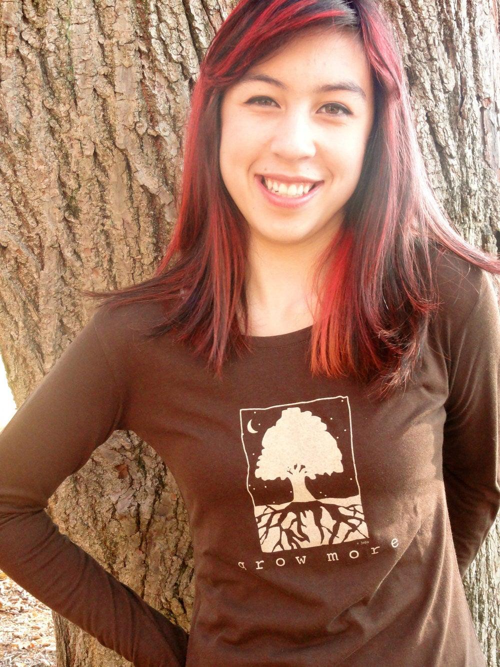 Woman wearing dark brown 'Grow More' tree long sleeve shirt made from bamboo and organic cotton, great for gardening and nature-inspired fashion.