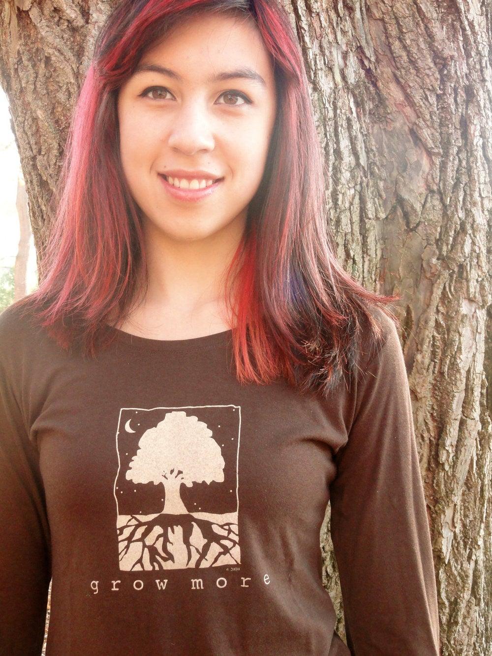 Close-up of woman modeling eco-friendly 'Grow More' tree long sleeve T-shirt in dark brown, made from bamboo and organic cotton blend.