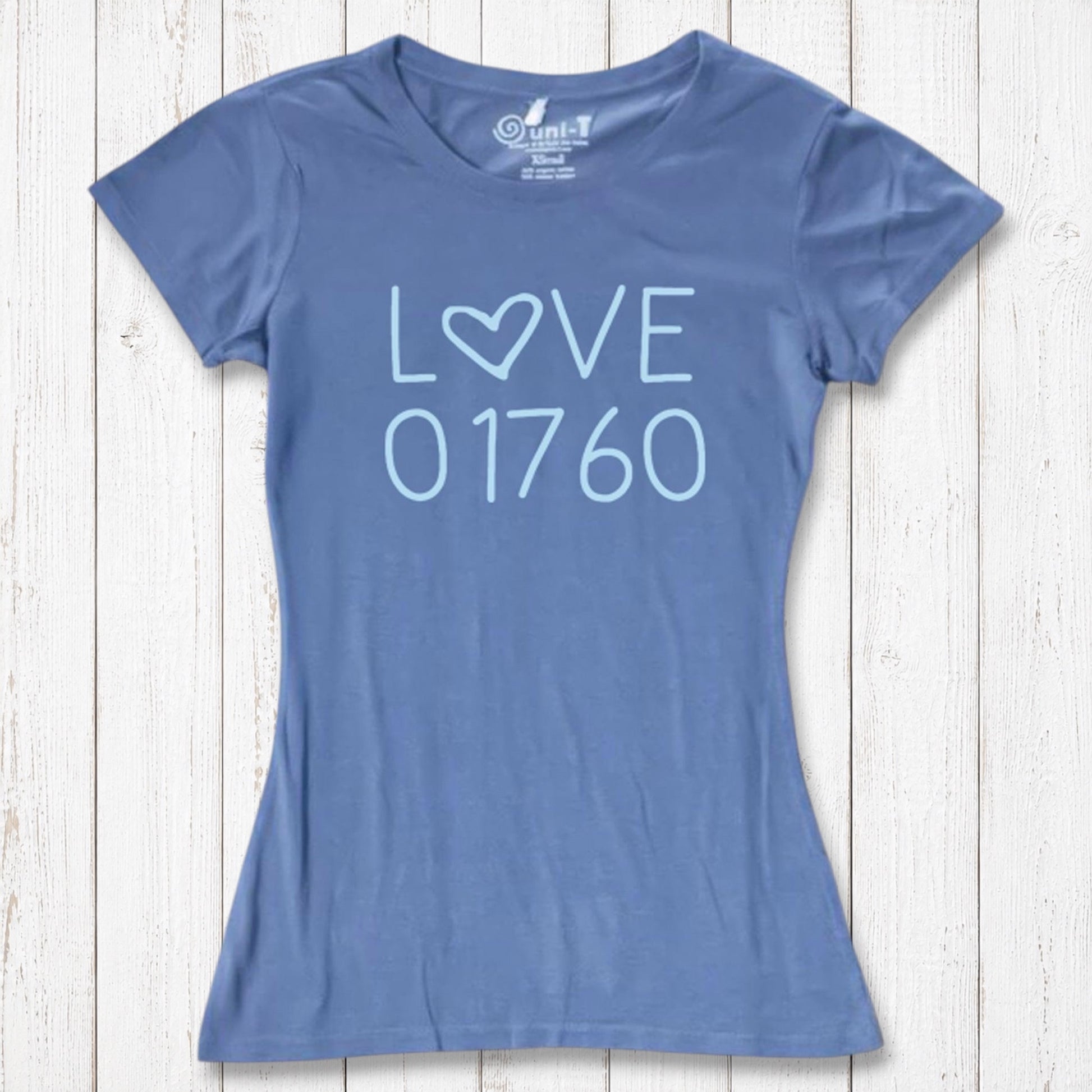 Blue women's T-shirt made of organic cotton and bamboo with 'LOVE' and '01760' printed in light blue, casual wear on white wooden background