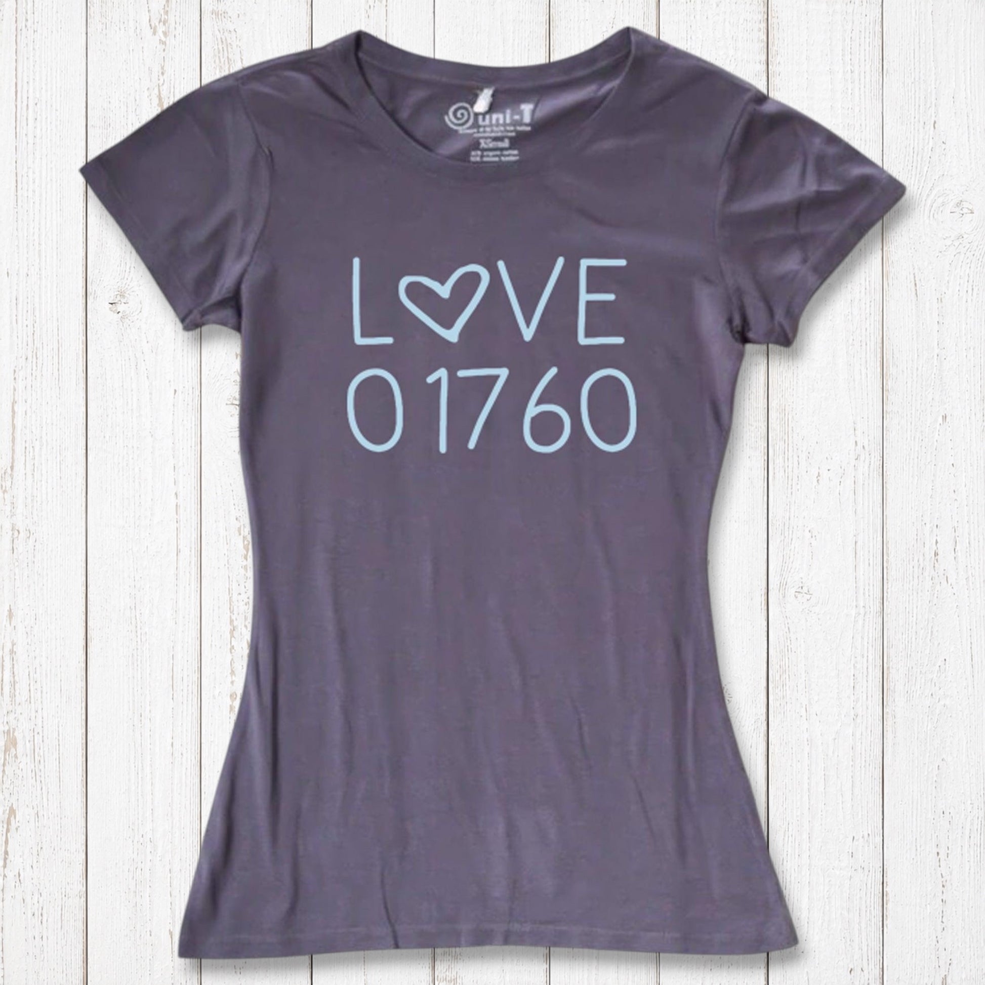 Dark gray women's T-shirt with light blue 'LOVE' graphic featuring a heart-shaped 'O' and the number 01760, laid flat on a white wooden background
