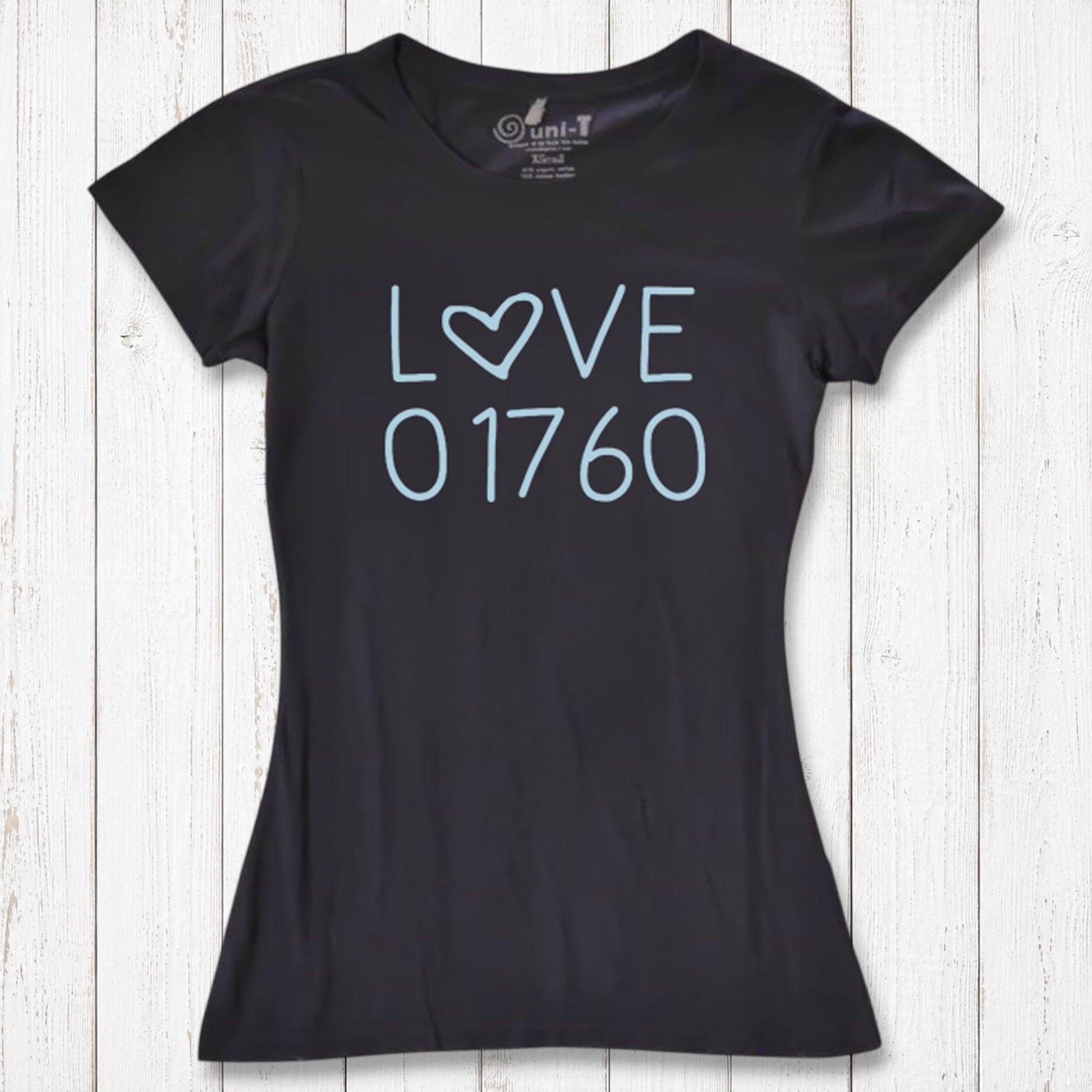Black women's T-shirt made of organic cotton and bamboo with a light blue 'LOVE' graphic and the number 01760, laid on white wooden background