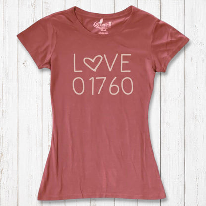 Rust-colored women's graphic T-shirt with the word LOVE and the number 01760 in white, made from organic cotton and bamboo, laid on a white wooden background