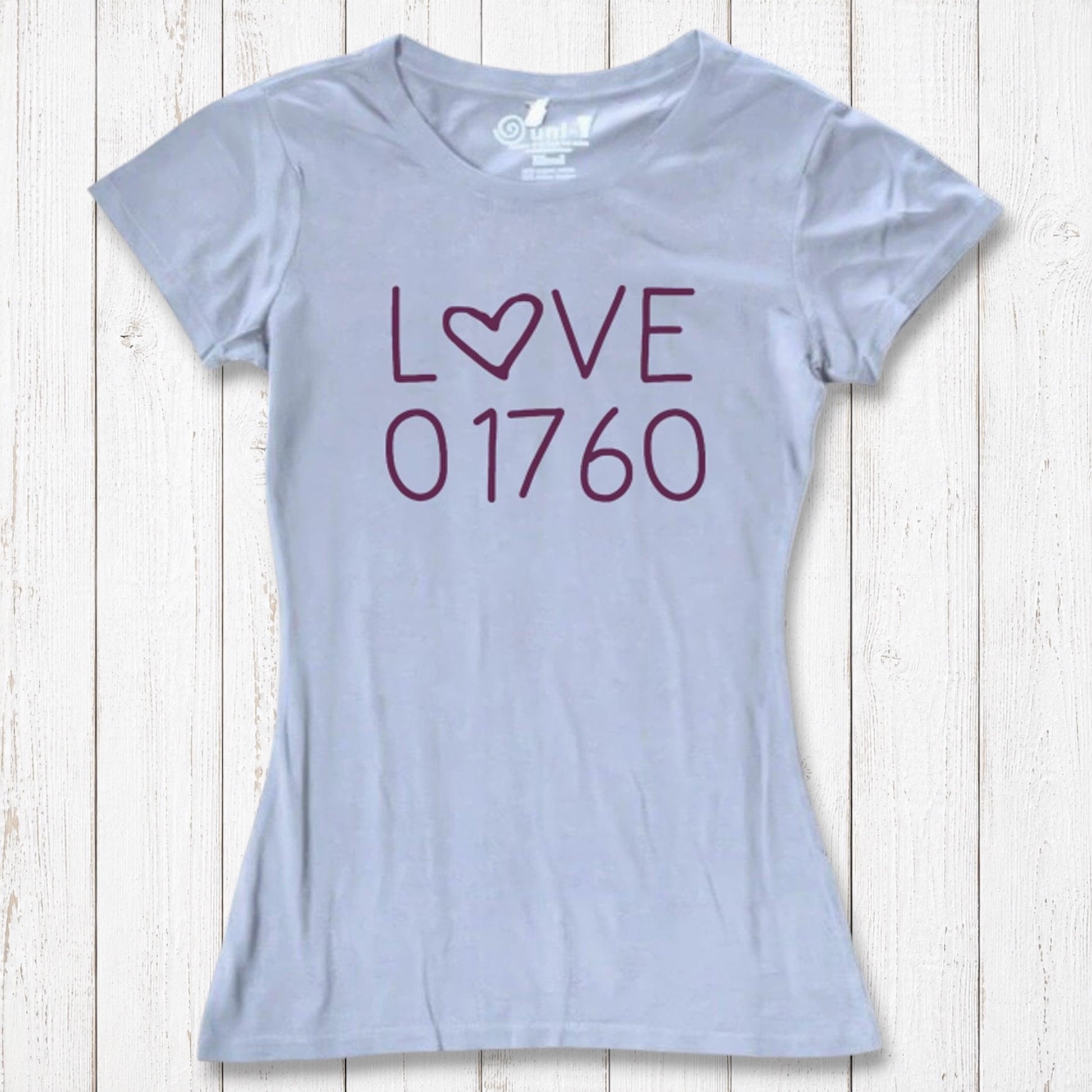 Light gray women's T-shirt made of organic cotton and bamboo with 'LOVE' printed in purple, featuring a heart-shaped 'O', laid flat on white wooden background