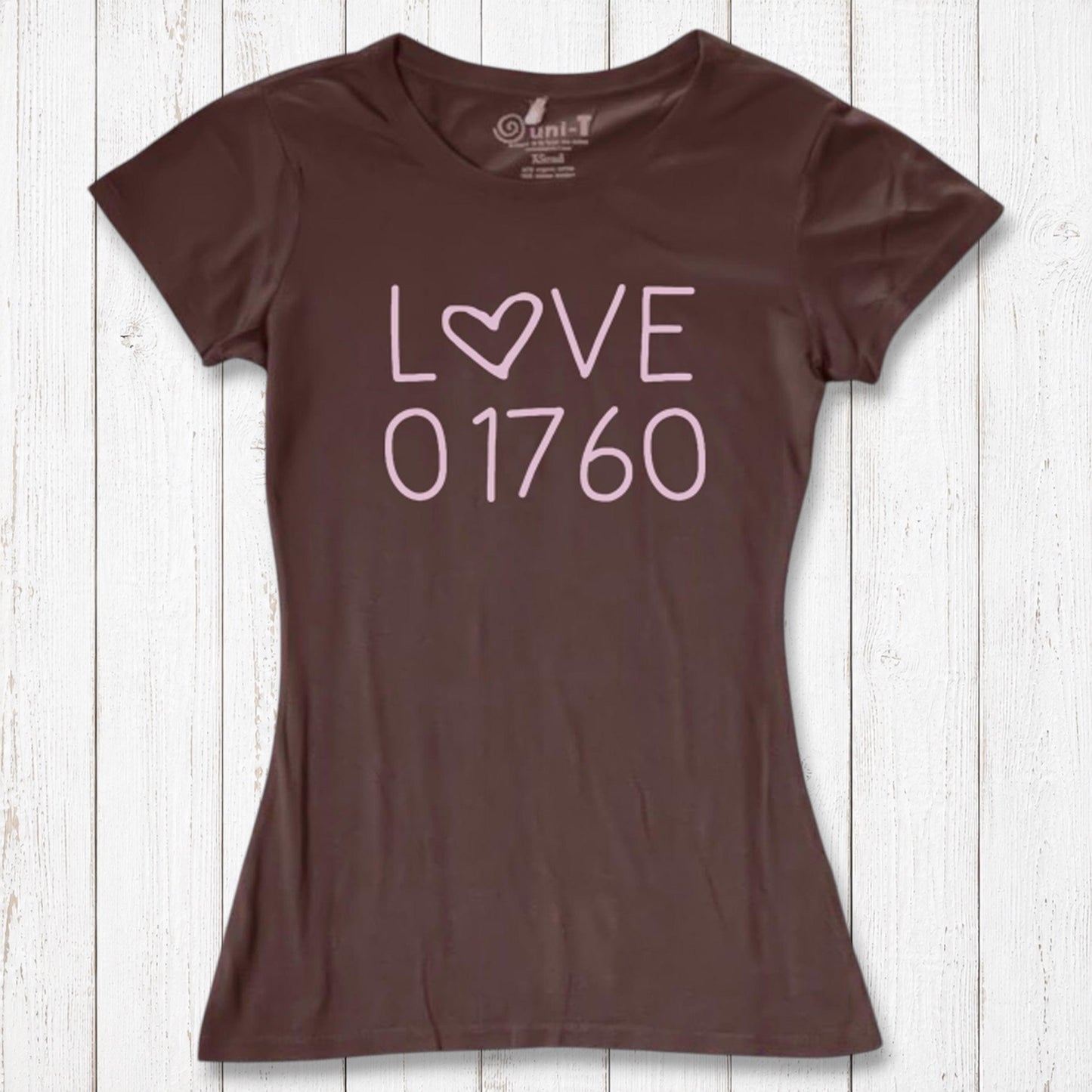 Brown women's graphic T-shirt with the word LOVE and the number 01760 in pink, made of organic cotton and bamboo, laid on white wooden background