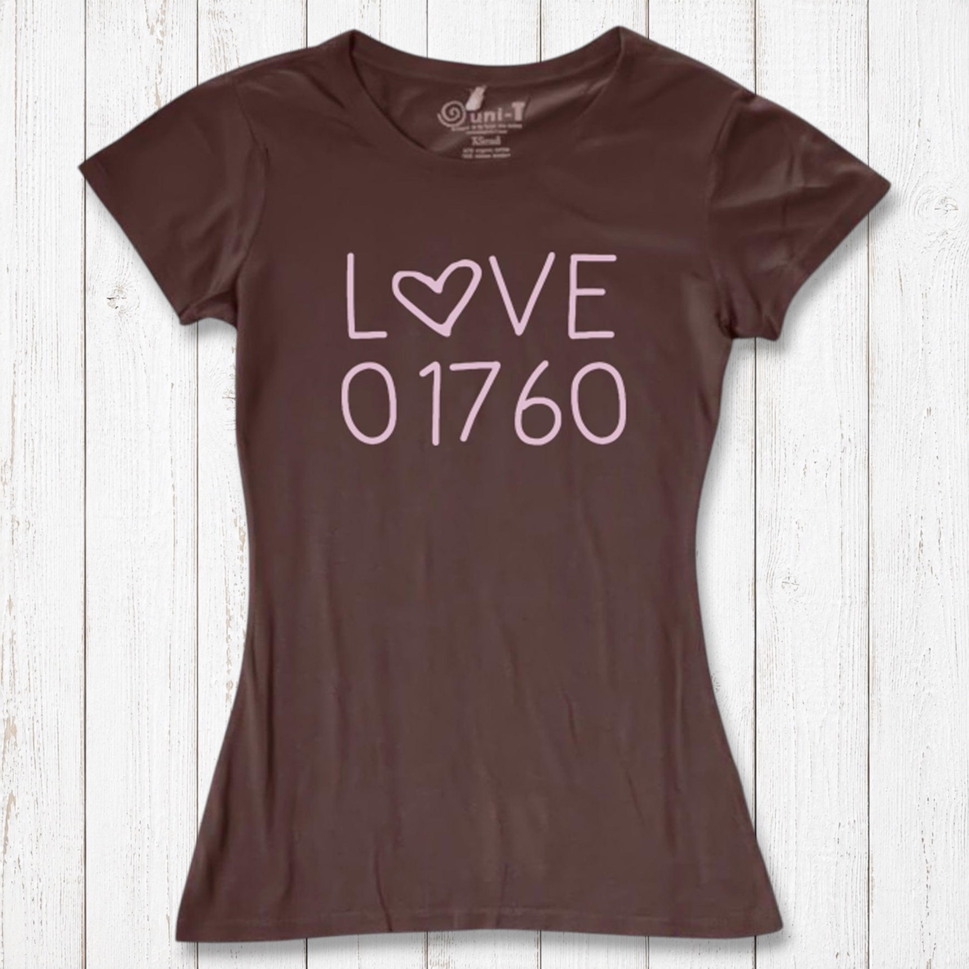 Brown women's graphic T-shirt with the word LOVE and the number 01760 in pink, made of organic cotton and bamboo, laid on white wooden background