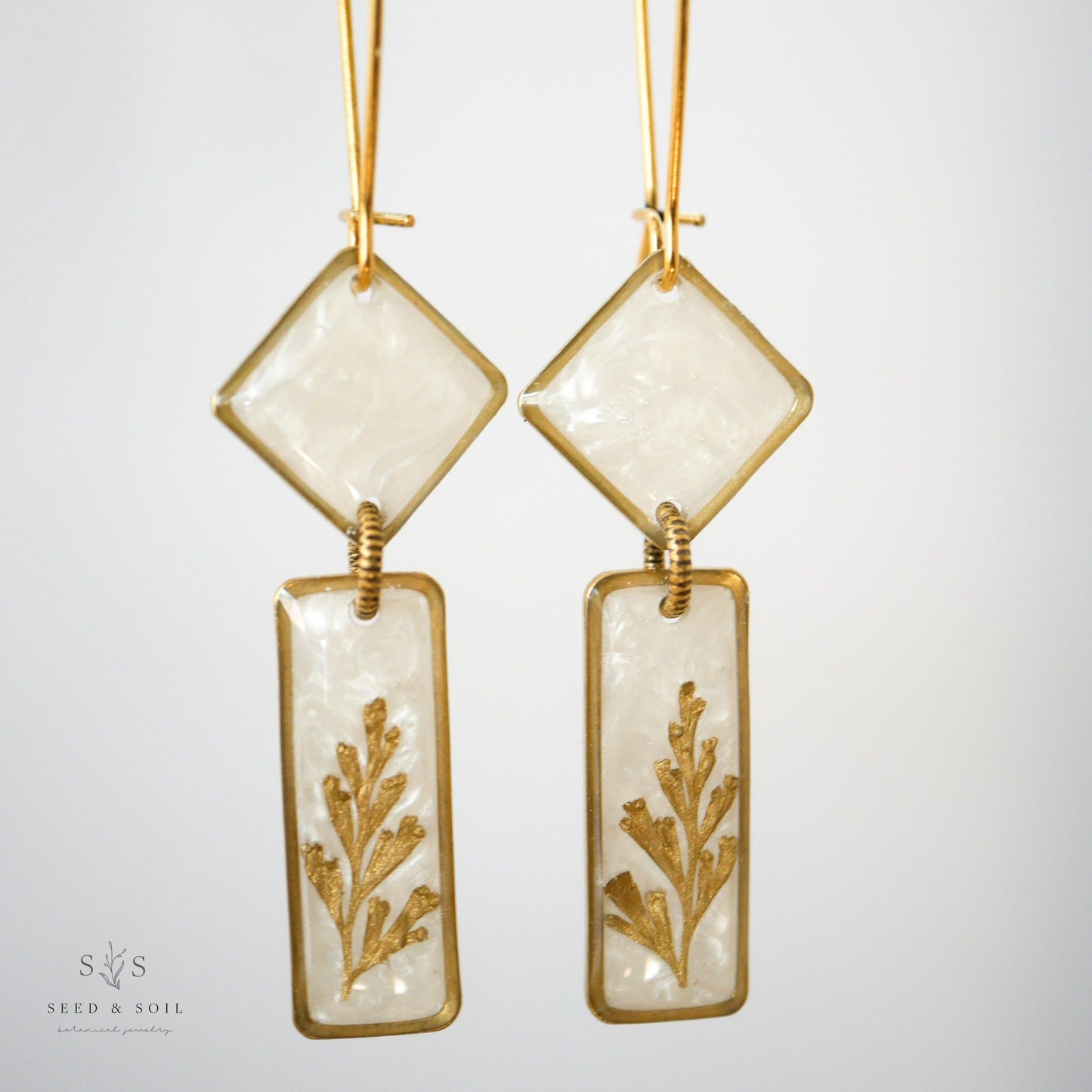 Close-up of Midas Art Deco Dangle Earrings showcasing vintage-inspired brass frames, gold plating, and botanical fern design.