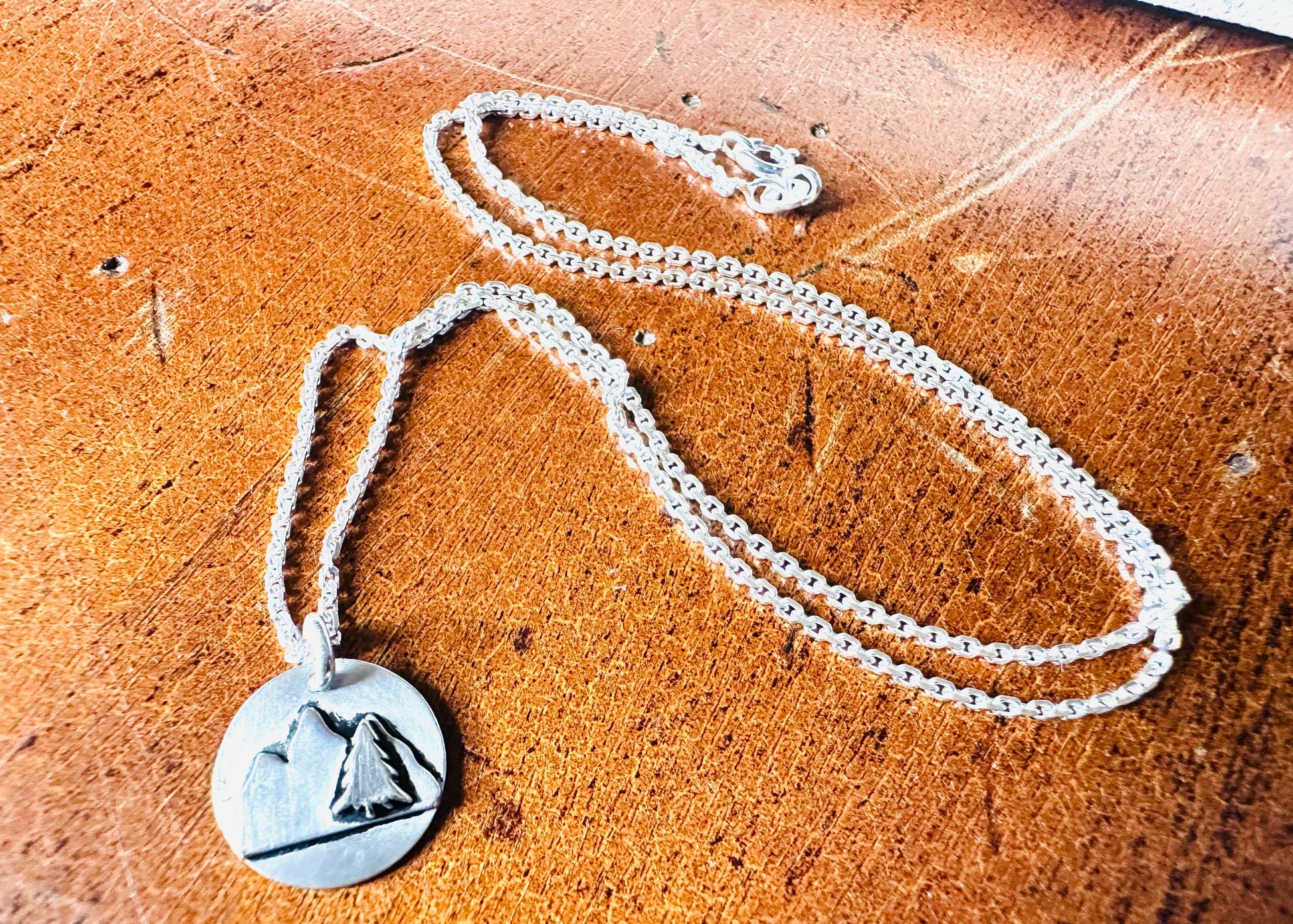 Silver mountain pendant necklace on wooden surface