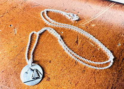 Silver mountain pendant necklace on wooden surface