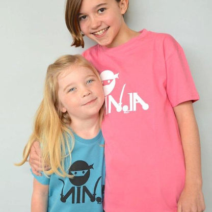 Two children wearing Kids' Ninja Organic Cotton T-Shirts in pink and teal, showcasing fun and eco-friendly graphic tees by Uni-T.