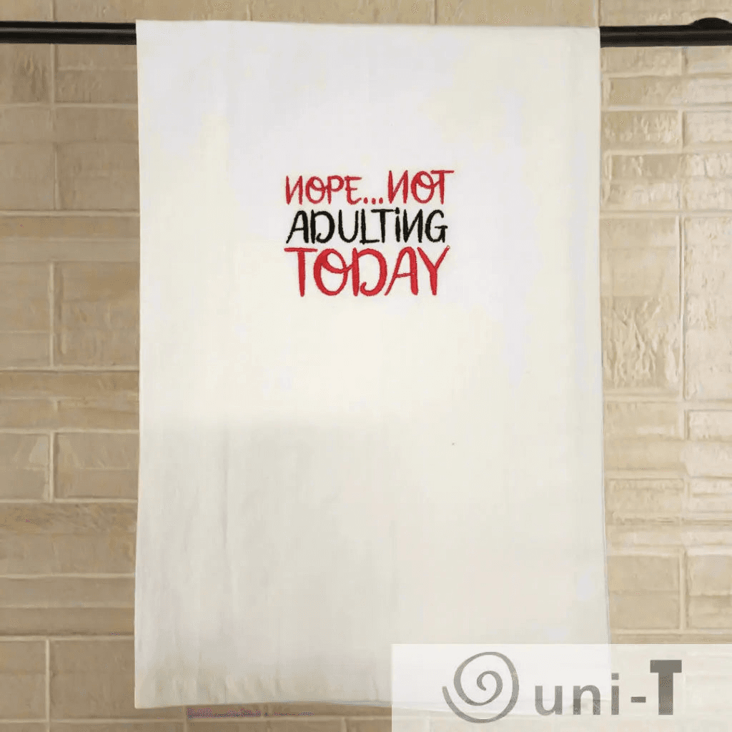 Nope... not adulting Towel - Funny Embroidered Towel hanging on a rod against a tiled wall, perfect humorous touch for any kitchen decor.