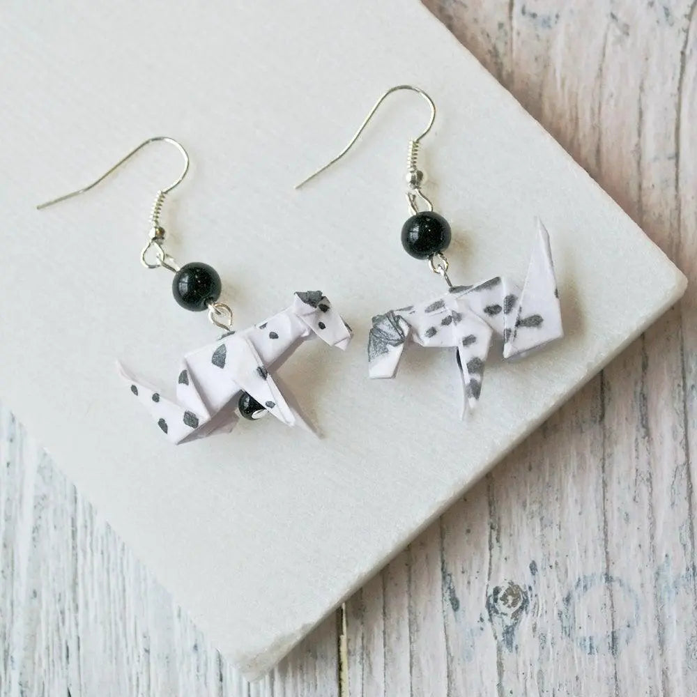 Dalmatian Origami Dog Earrings set displayed on white surface, featuring black-spotted paper dogs and elegant hook design for easy wear.
