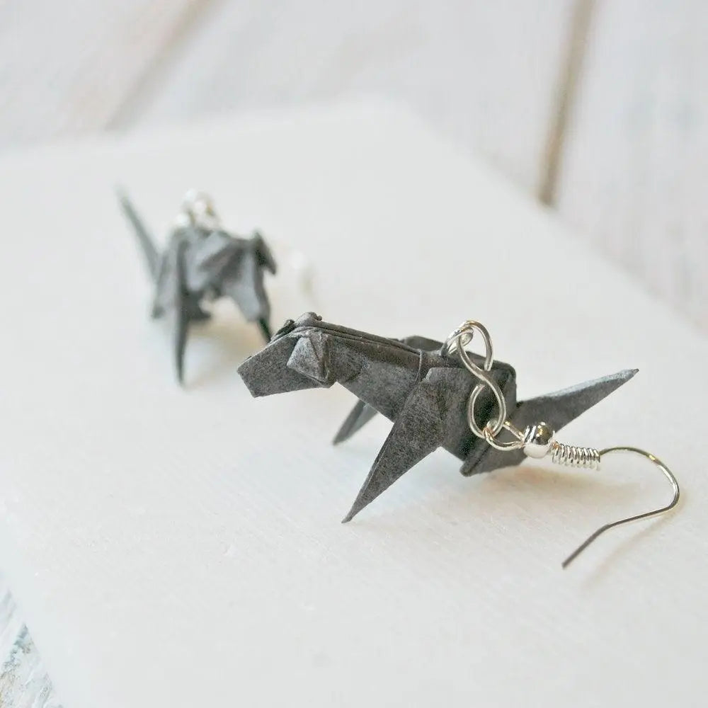 Grey origami dog earrings crafted from folded paper and sealed with acrylic, featuring a unique geometric design and silver hooks.