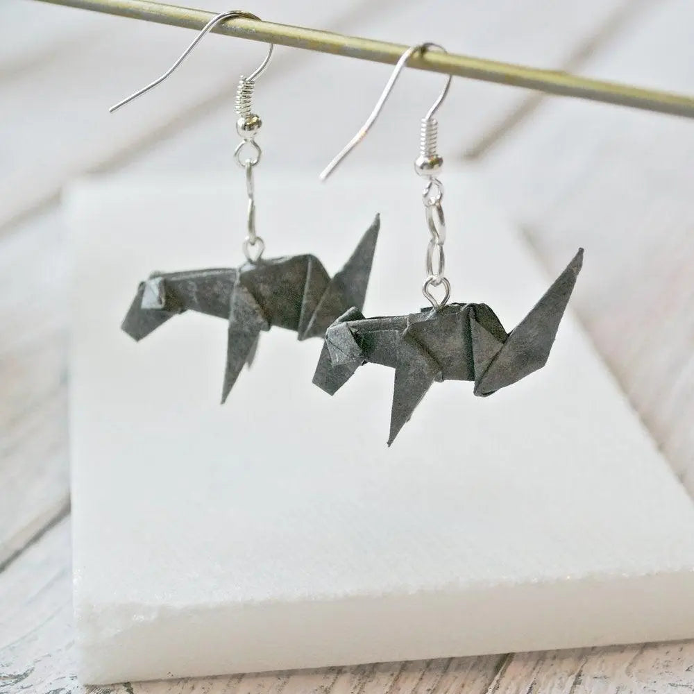 Hanging grey origami dog earrings with intricate paper folds and silver ear wires, showcasing unique paper craft jewelry style.