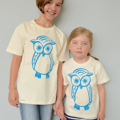 Two children wearing cream Kids' Organic Cotton Owl T-Shirts with blue owl print. Uni-T eco-friendly matching wildlife tops for siblings.