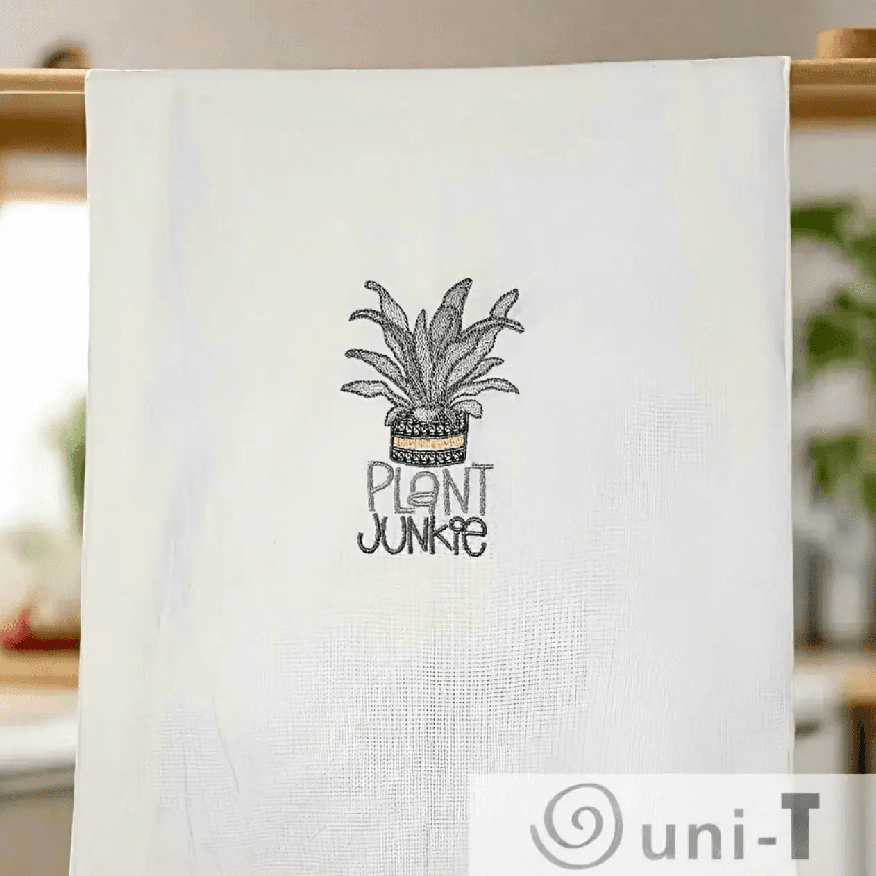 Plant Junkie Embroidered Towel hanging in kitchen setting. Fun plant-themed design adds charm to home essentials and small gift ideas.