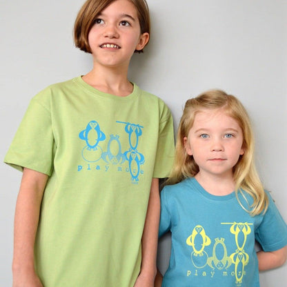 Two children wearing Kids' Penguin Organic Cotton T-Shirts in green and blue, featuring playful sea life penguins and 'play more' slogan.