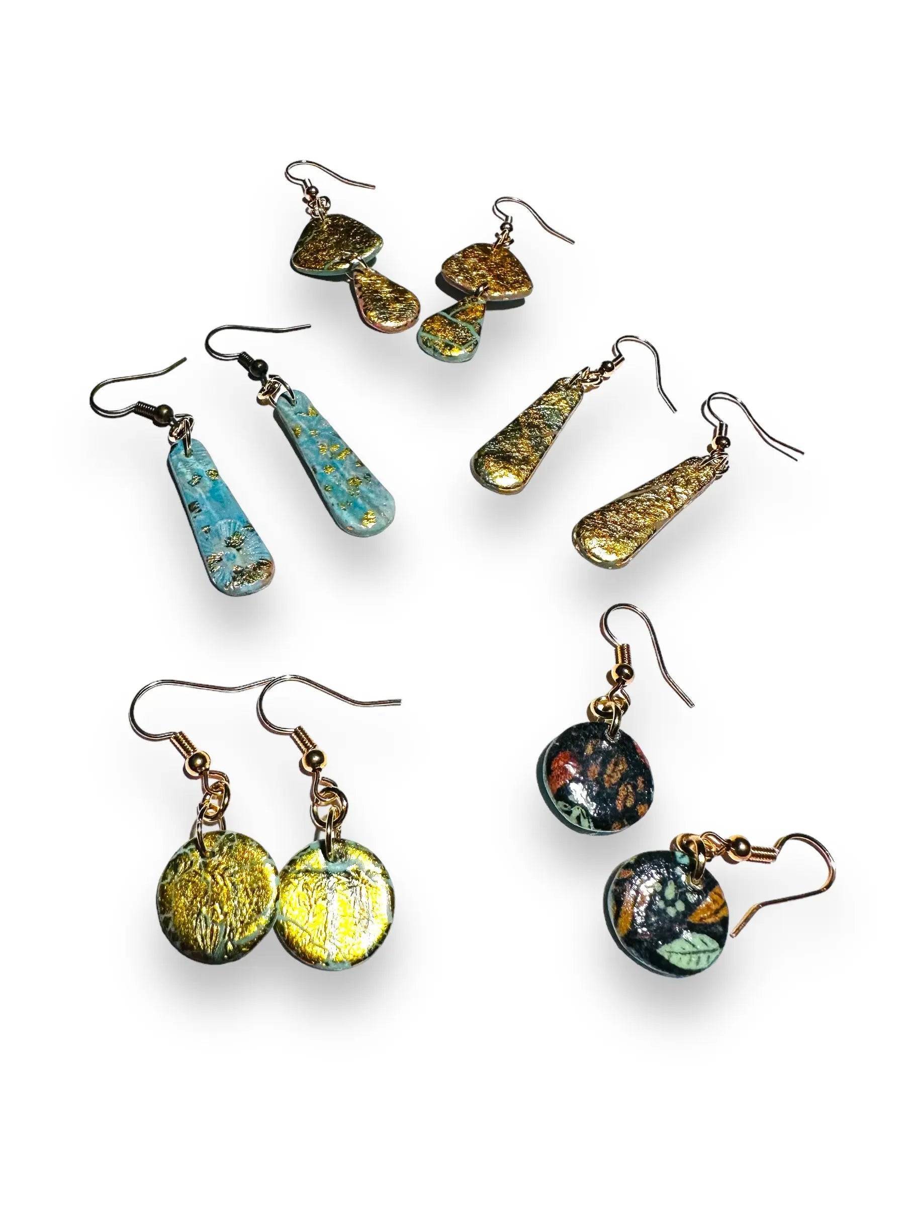 Assorted polymer clay earrings in various shapes and colors with gold leaf accents and gold plated earwires, ideal for affordable gifting.