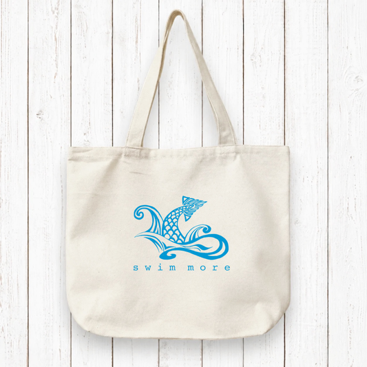 Swimmers Gift Canvas Tote with 'Swim More' fish wave design in blue ink on organic cotton. Eco-friendly tote ideal for swim gear or beach days.