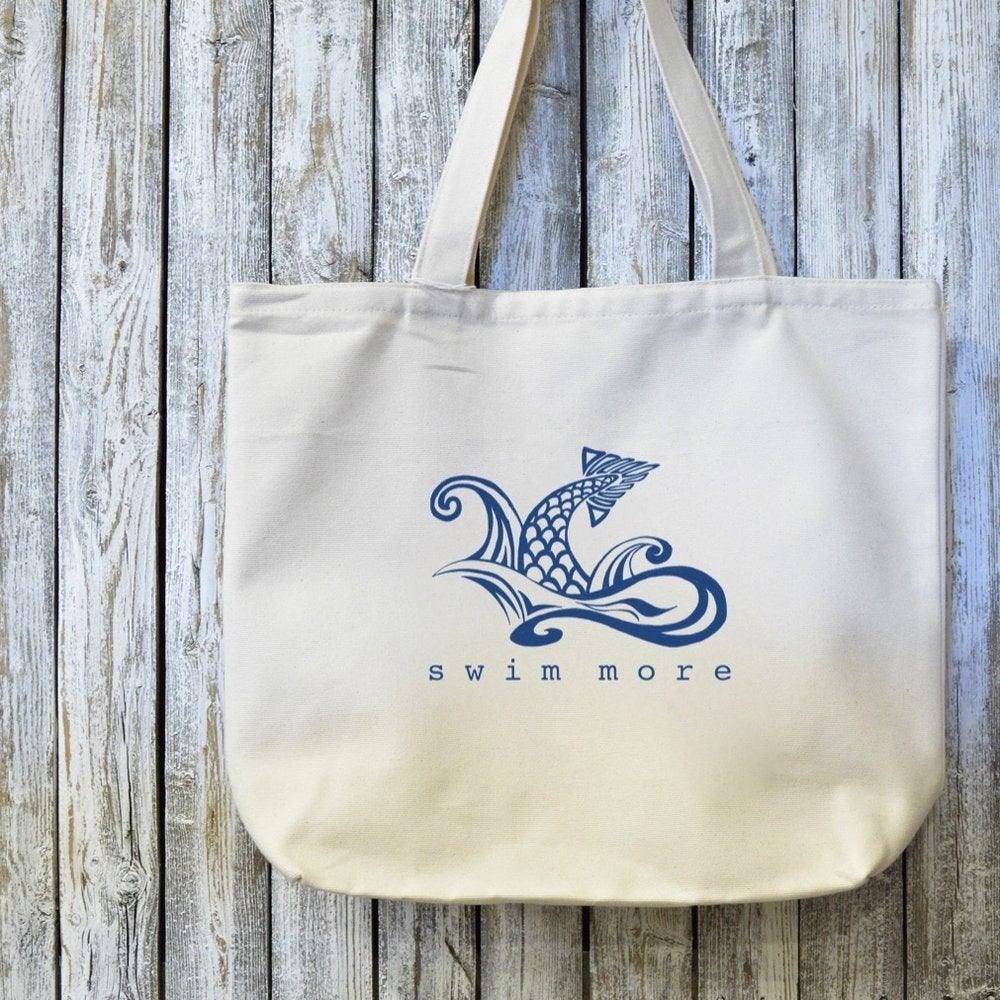 Organic cotton tote bag featuring 'Swim More' design with artistic fish and waves. Great swimmers gift and sustainable everyday carry bag.