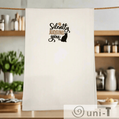 Silently Judging You Towel - Cat Embroidered | Kitchen Sass hanging in cozy kitchen, perfect small gift for cat lovers and home chefs.