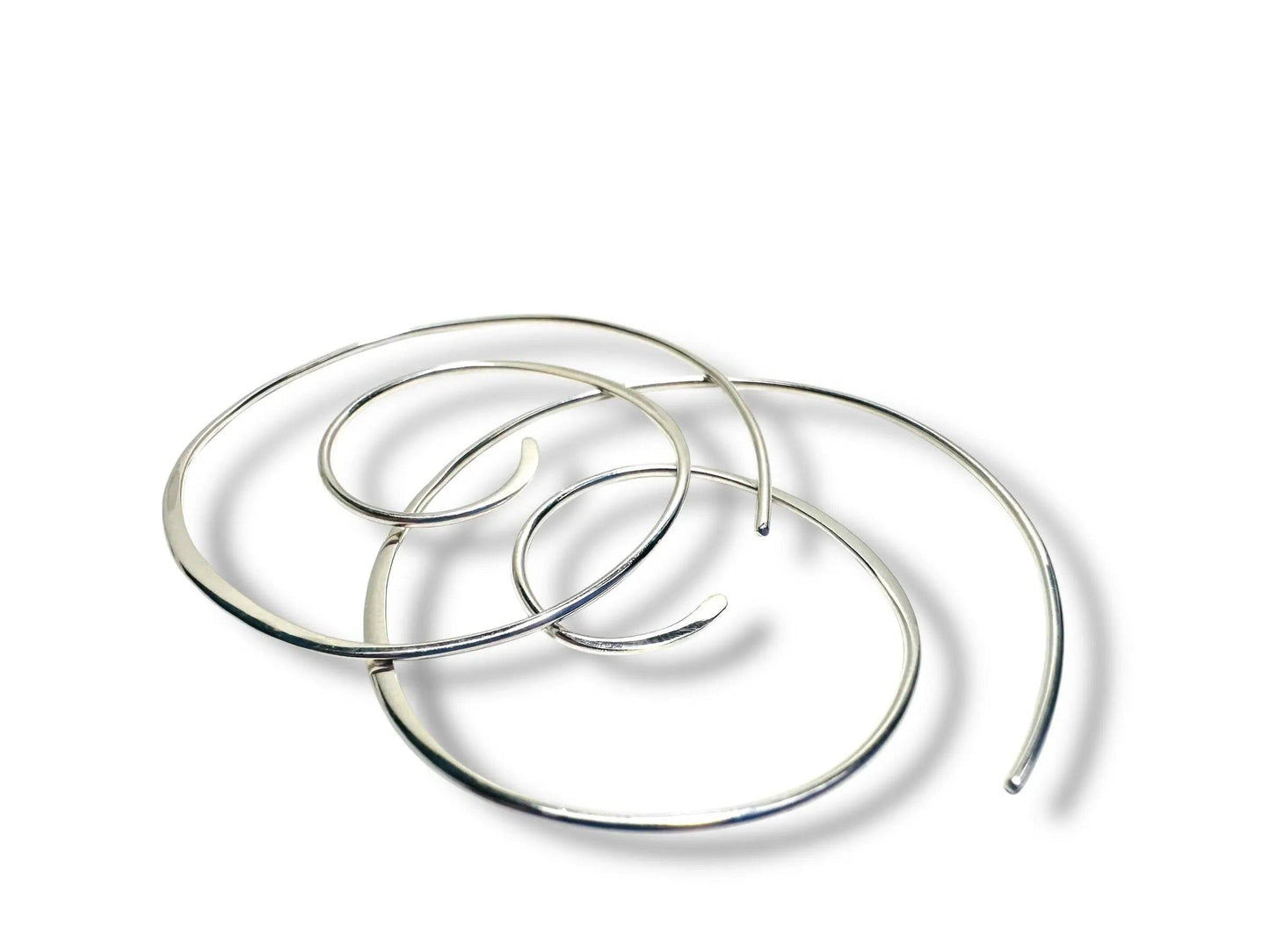 Silver Swirl Hoops - Set of sterling silver swirl earrings shown overlapping on a white background. Sleek, modern hoops for stylish accessorizing.