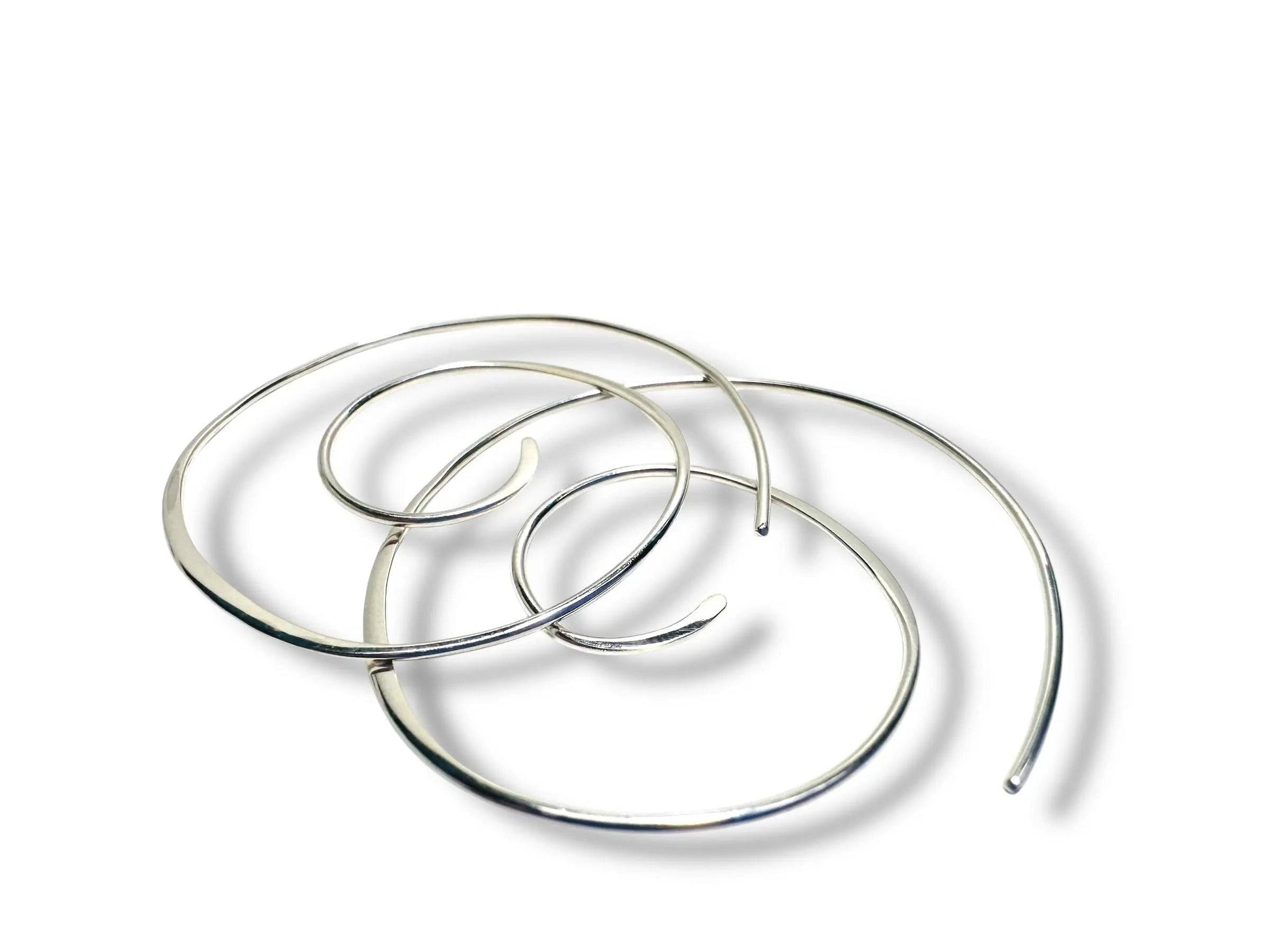 Silver Swirl Hoops - Set of sterling silver swirl earrings shown overlapping on a white background. Sleek, modern hoops for stylish accessorizing.