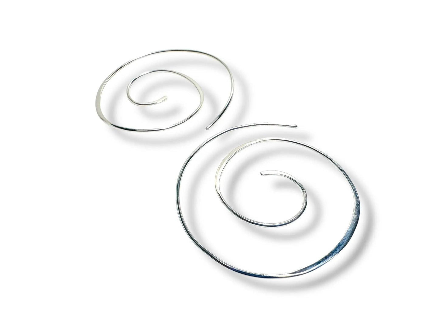 Silver Swirl Hoops - Pair of 1.5” sterling silver swirl earrings laid flat on a white surface. Lightweight, spiral design perfect for everyday wear.