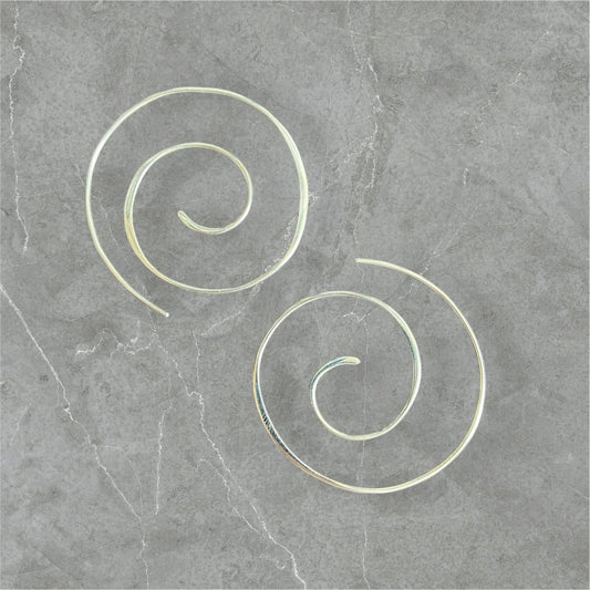 Silver Swirl Hoops - Sterling silver swirl earrings with a 1.5” diameter, displayed on a gray stone background. Elegant and minimalist jewelry design.