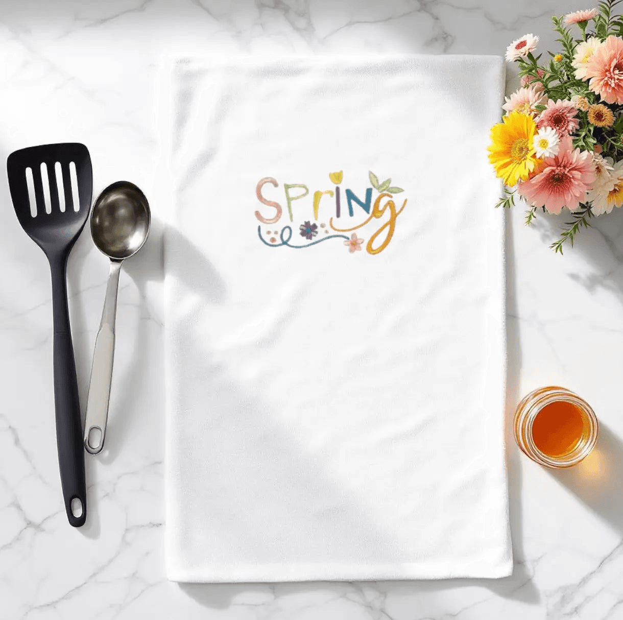 Spring Embroidered Towel - Embroidered Kitchen Towel | Durable, shown on marble countertop with utensils and flowers, ideal for seasonal kitchen decor.
