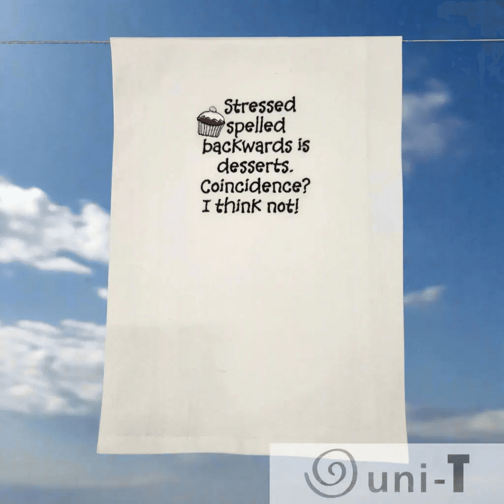 Stressed Desserts Towel - Embroidered | Absorbent & Fun shown outdoors on a clothesline, highlighting its playful design and quality fabric for kitchen use.