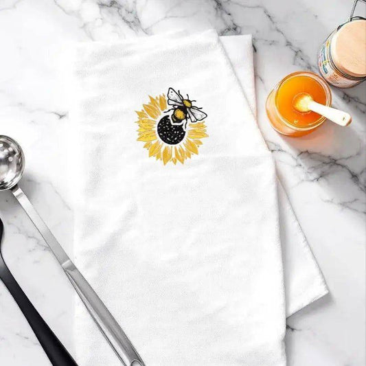 Sunflower Bee Embroidered Towel on marble counter with honey jar and ladle, perfect for adding nature-inspired charm to kitchen decor.