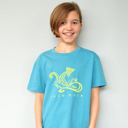 Child wearing Kids' Swim Organic Cotton T-Shirt in teal blue with yellow swimmer graphic and 'swim more' text, eco-friendly athletic shirt by Uni-T.