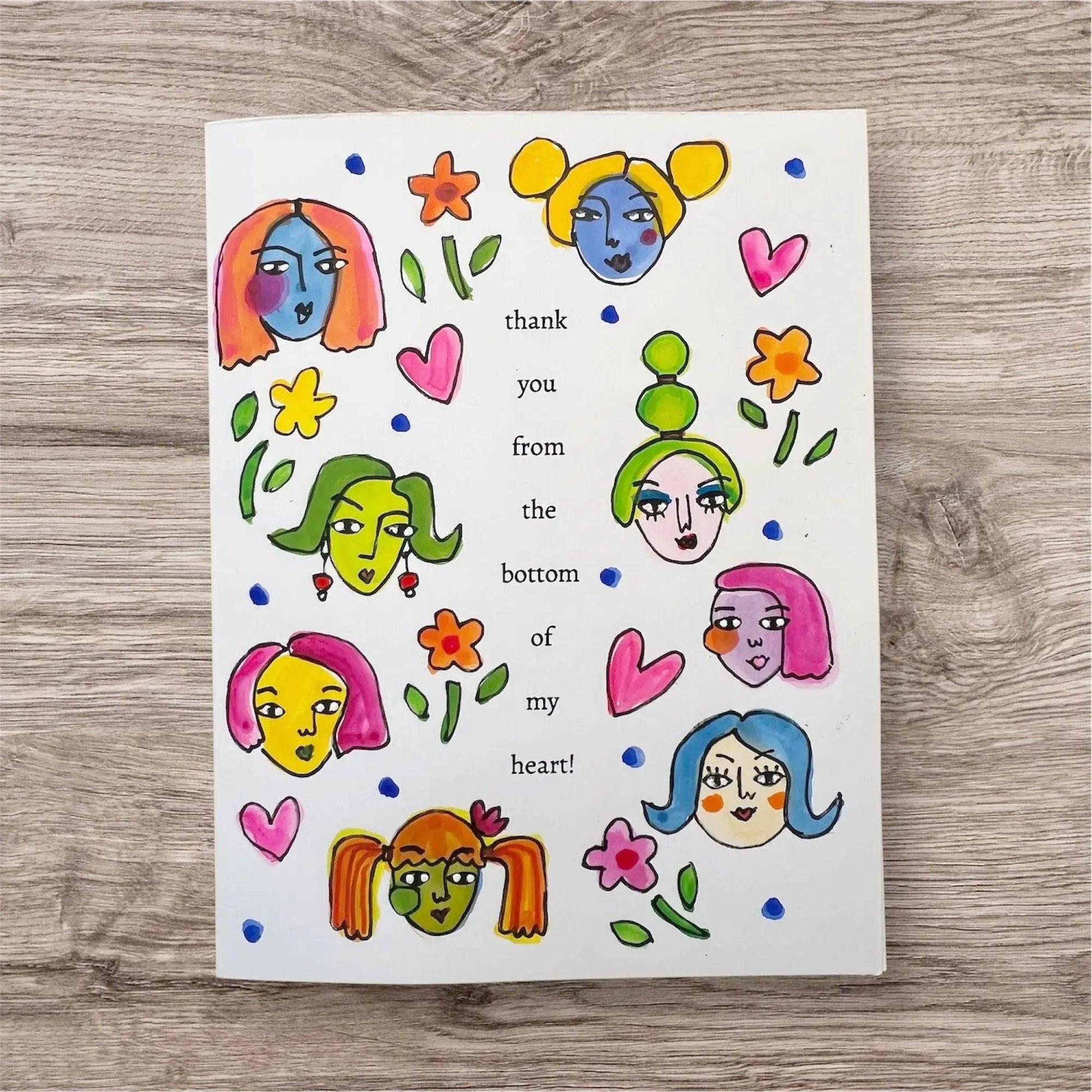 Hand-painted Good Vibe Tribe greeting card featuring colorful illustrated female faces, flowers, and the message 'thank you from the bottom of my heart!'