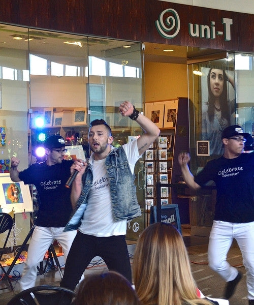 Live performance at Uni-T store with dancers and singer wearing 'Celebrate Tolerate^' graphic T-shirts supporting LGBTQ+ unity and diversity.