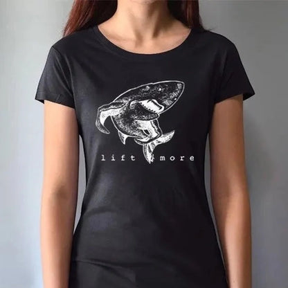 Black fitted women's shark graphic T-shirt with 'Lift More' slogan. Bamboo and organic cotton blend for sustainable gym wear.