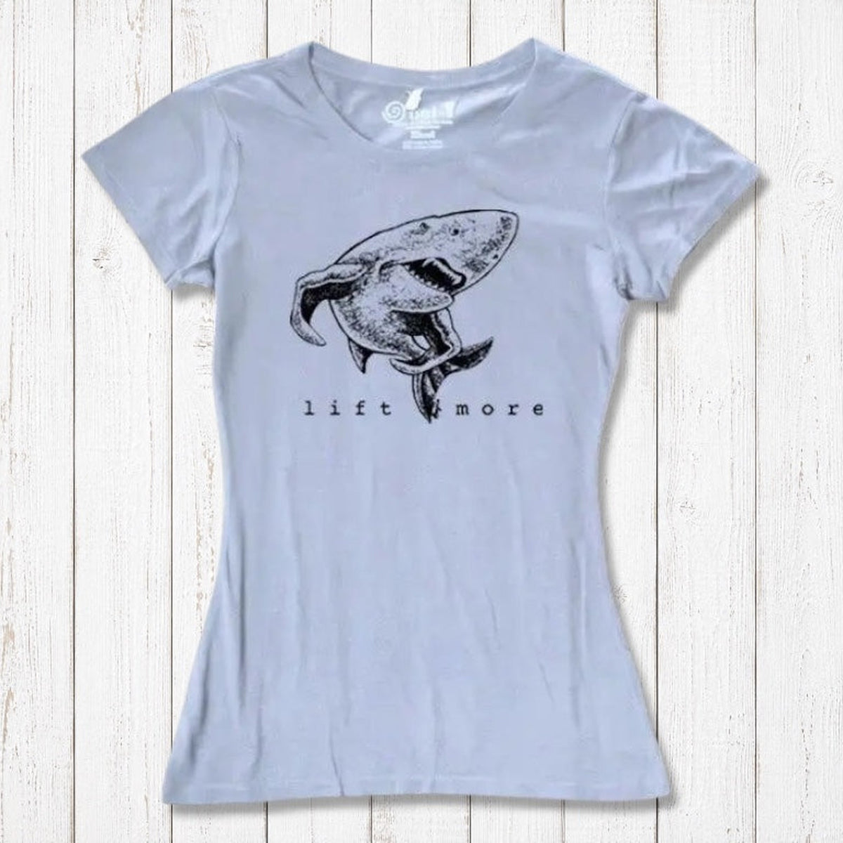Light blue women's shark graphic T-shirt with 'Lift More' text. Sustainable bamboo and organic cotton gym motivation tee.