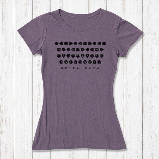 Purple women's T-shirt with black graphic print of a vintage typewriter keyboard and the phrase write more, made from soft organic cotton, laid on white wooden background