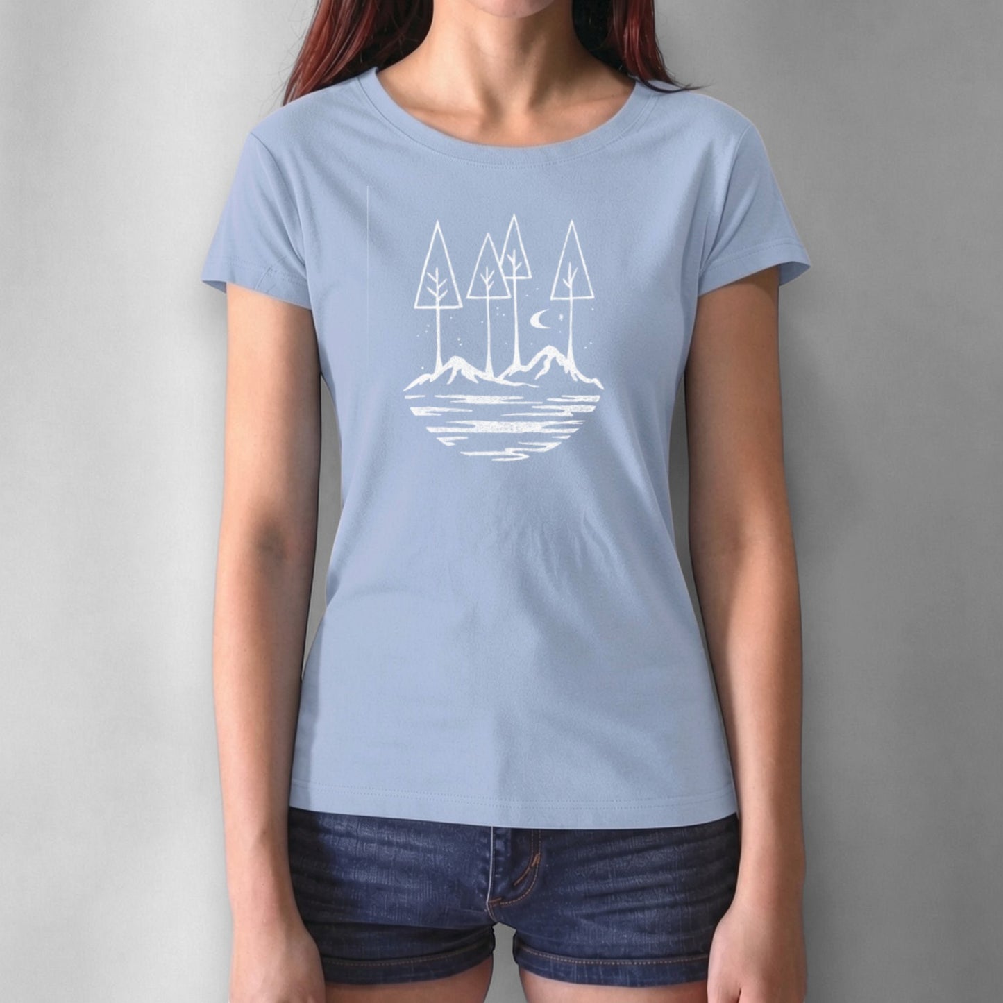 Light blue women's graphic tee with black forest and mountain illustration. Sustainable bamboo and cotton blend for nature enthusiasts.
