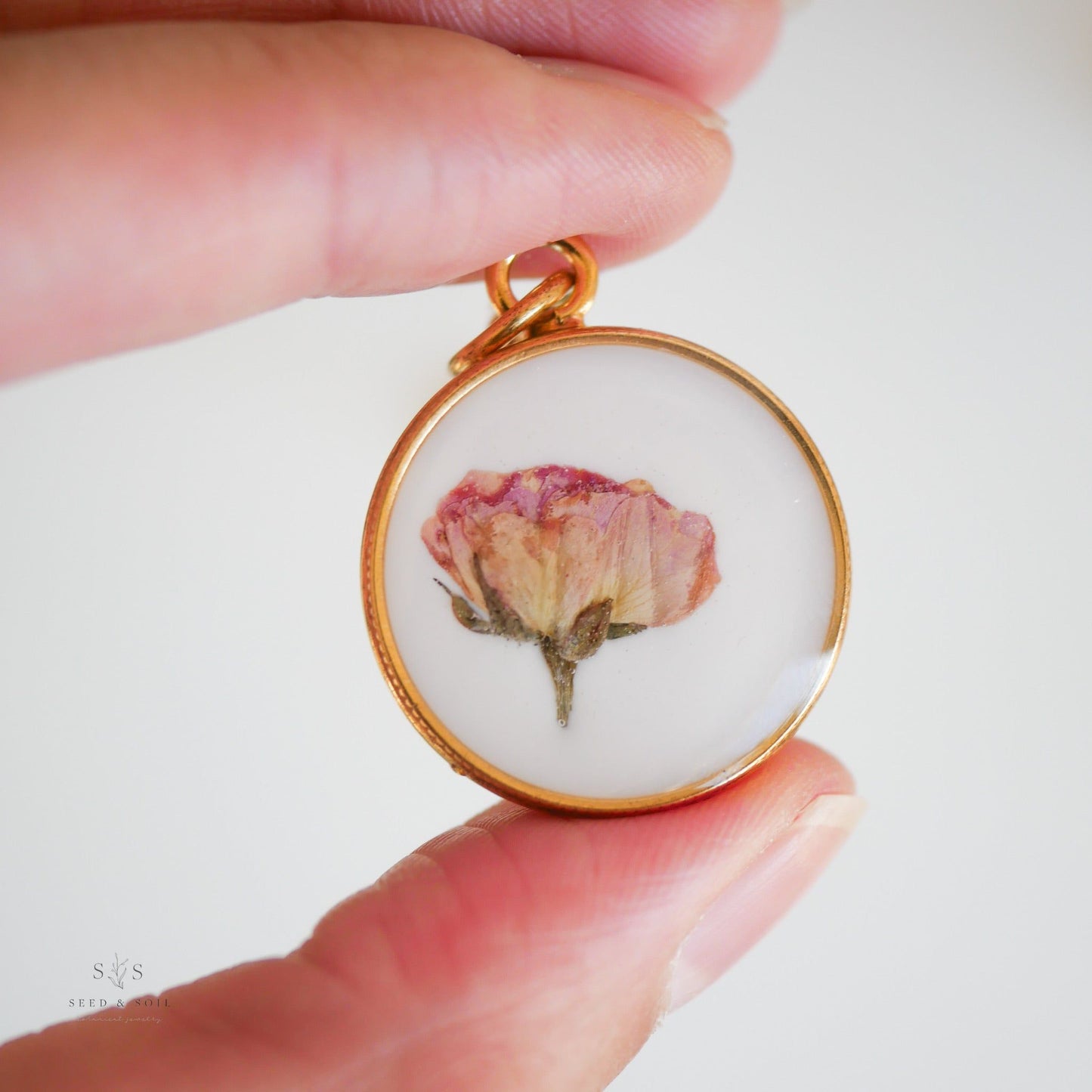 Hand holding gold Valentine Round Rose Necklace pendant with dried rose, showcasing its artisan craftsmanship and vintage appeal.