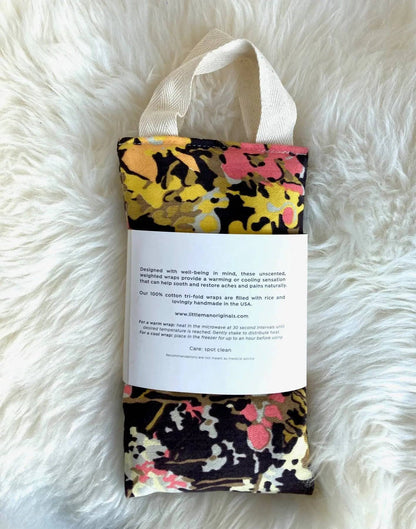 Back view of therapy wrap with yellow and pink floral print, showing product label with usage and care instructions.