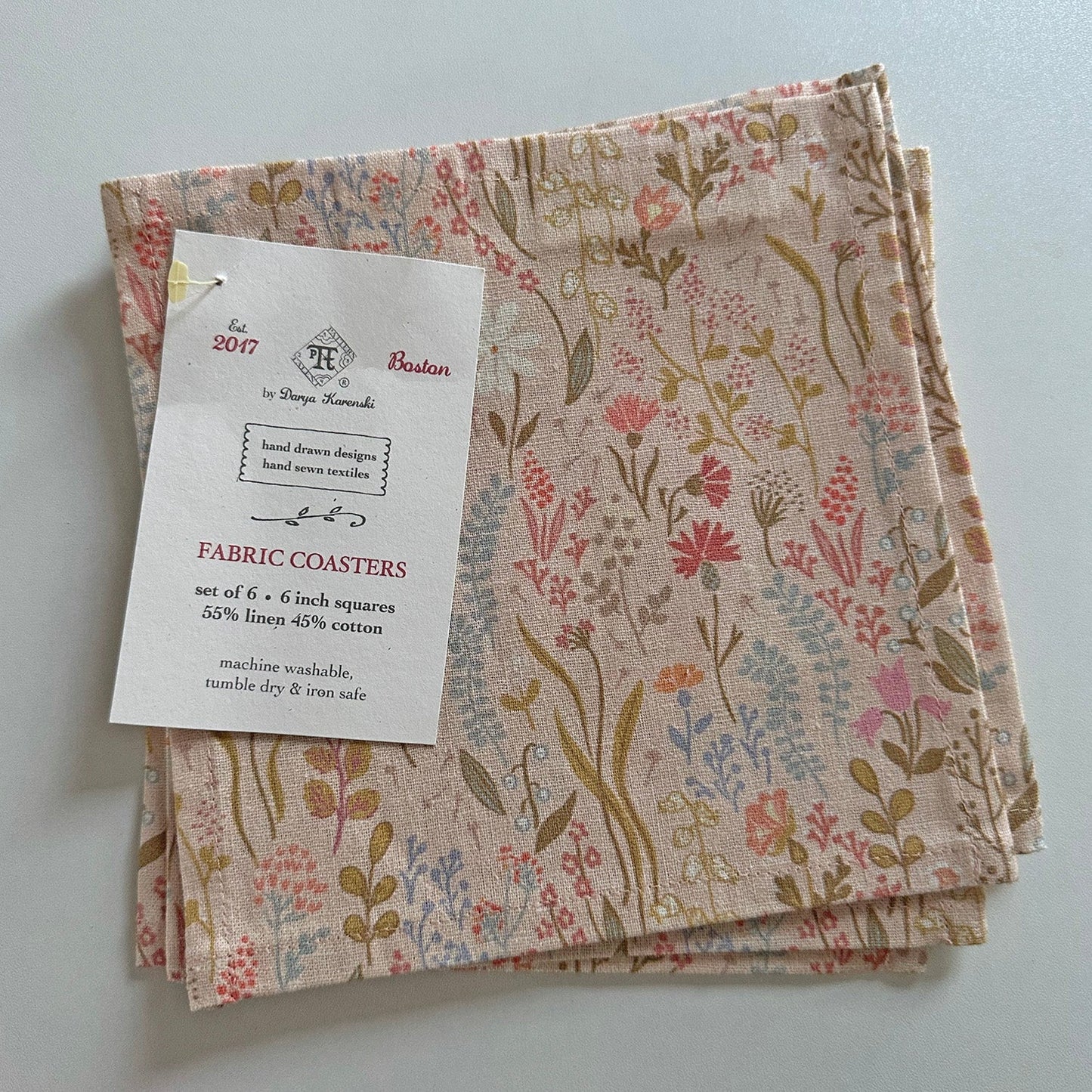 Set of fabric coasters with pink floral pattern and label