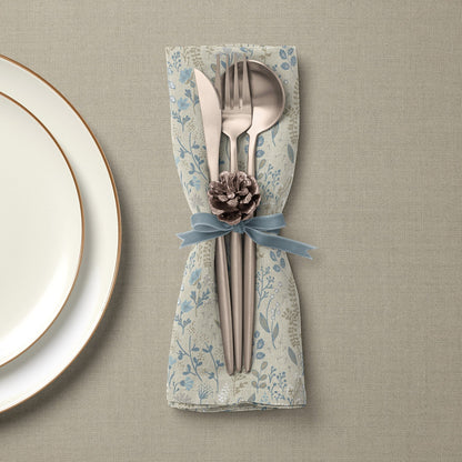Set of linen napkins with blue floral pattern and silverware tied with blue ribbon and pinecone