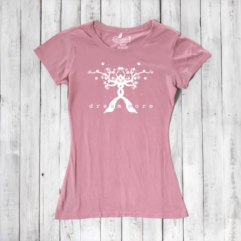 Pink Women's Motivational T-Shirt in Bamboo & Organic Cotton featuring white 'Dream More' tree graphic, laid flat on rustic wood.