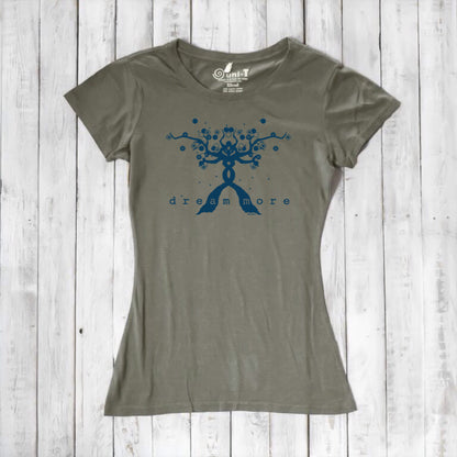 Olive green Women's Motivational T-Shirt in Bamboo & Organic Cotton with blue 'Dream More' tree graphic, flat lay on rustic wood.