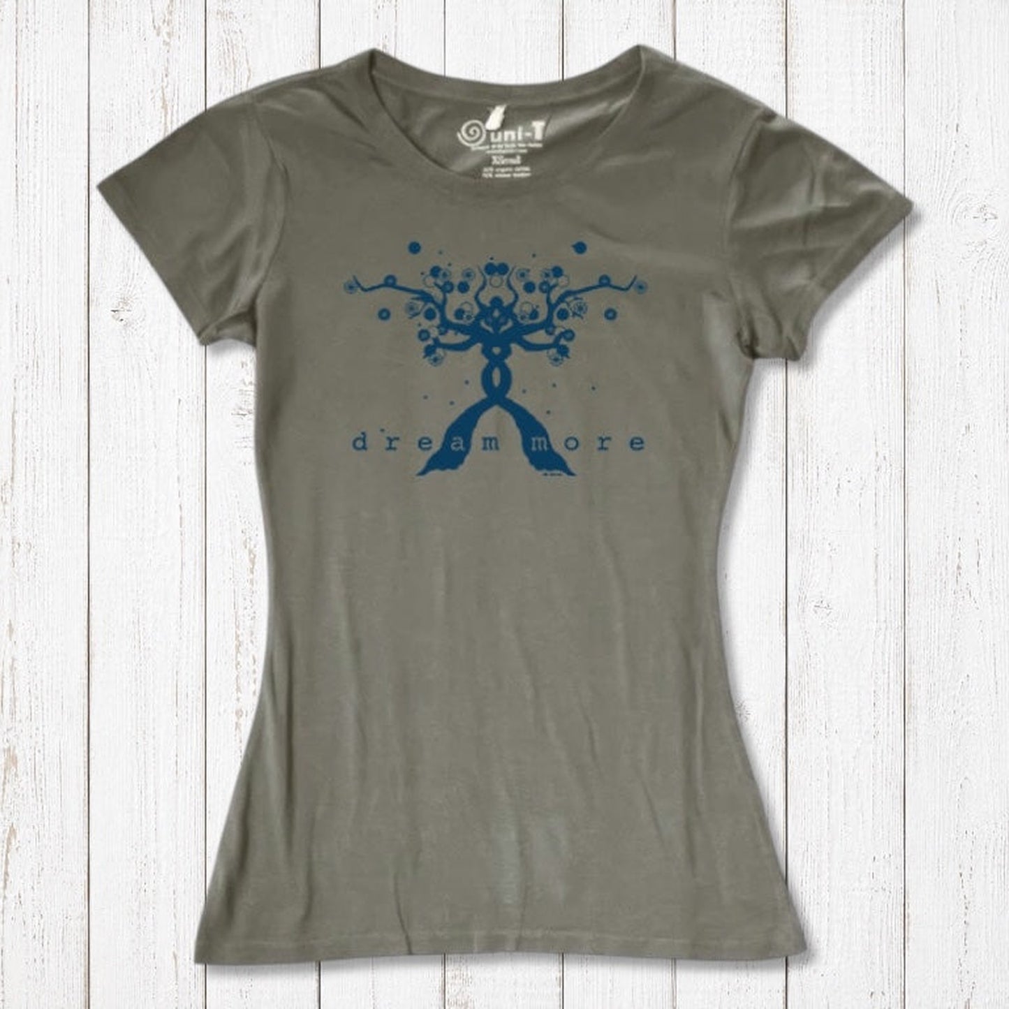 Olive green Women's Motivational T-Shirt in Bamboo & Organic Cotton with blue 'Dream More' tree graphic, flat lay on rustic wood.