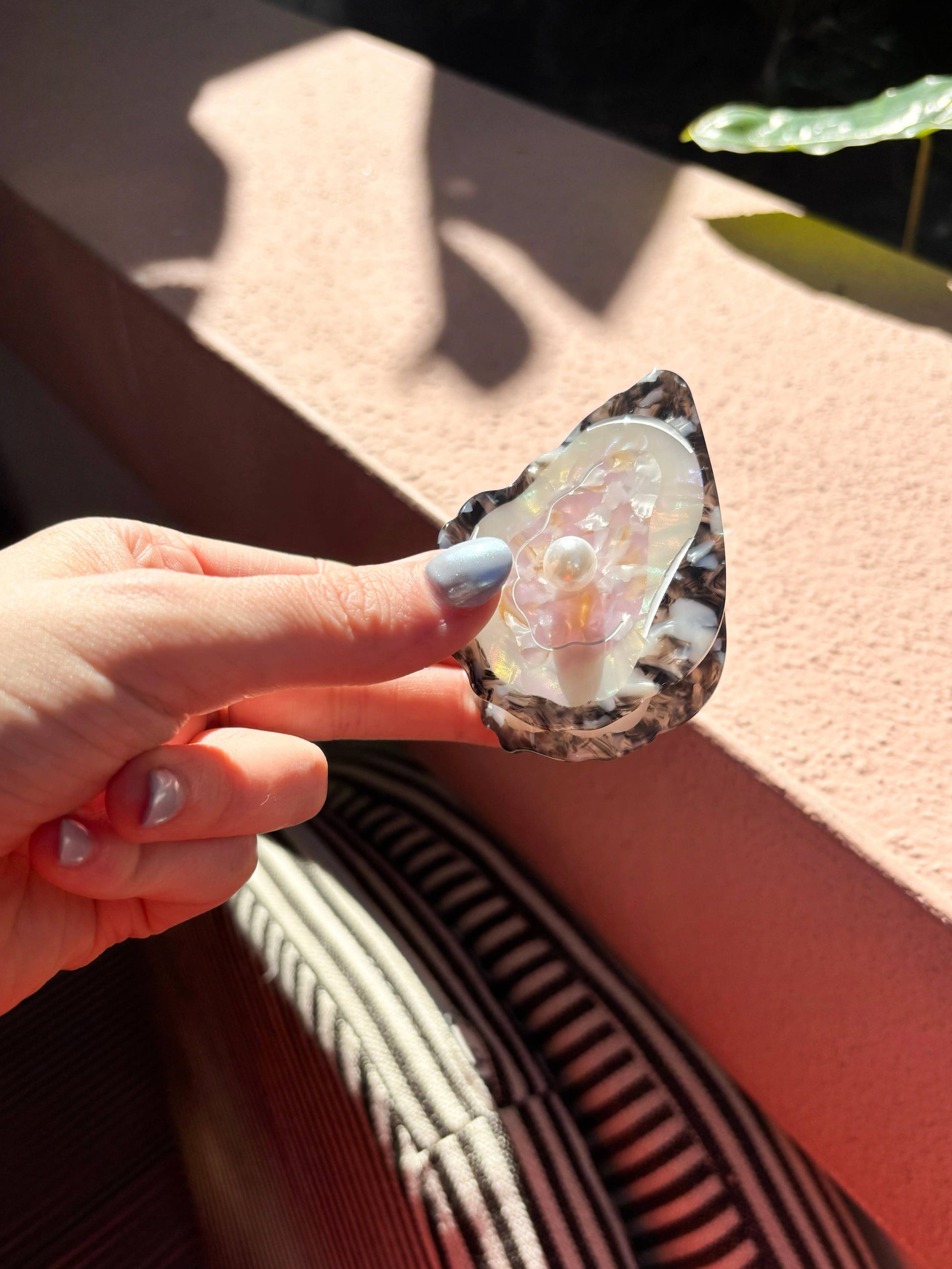 Line&Co Oyster Claw Clip with Pearl held in hand under natural light. Stylish hair accessory with realistic oyster shell look.