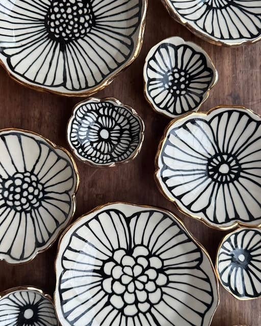 Set of 3" handmade flower-shaped jewelry dishes with black floral patterns and 22K gold accents, ideal for elegant ring or trinket storage.