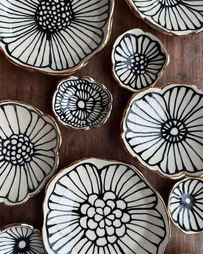 Set of 3" handmade flower-shaped jewelry dishes with black floral patterns and 22K gold accents, ideal for elegant ring or trinket storage.